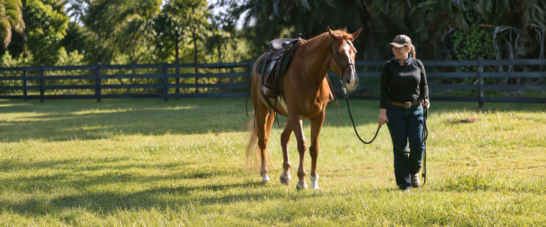 Erin leading a chestnut horse through the pasture