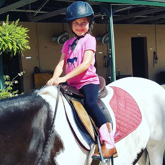 A young camper smiling on a paint pony
