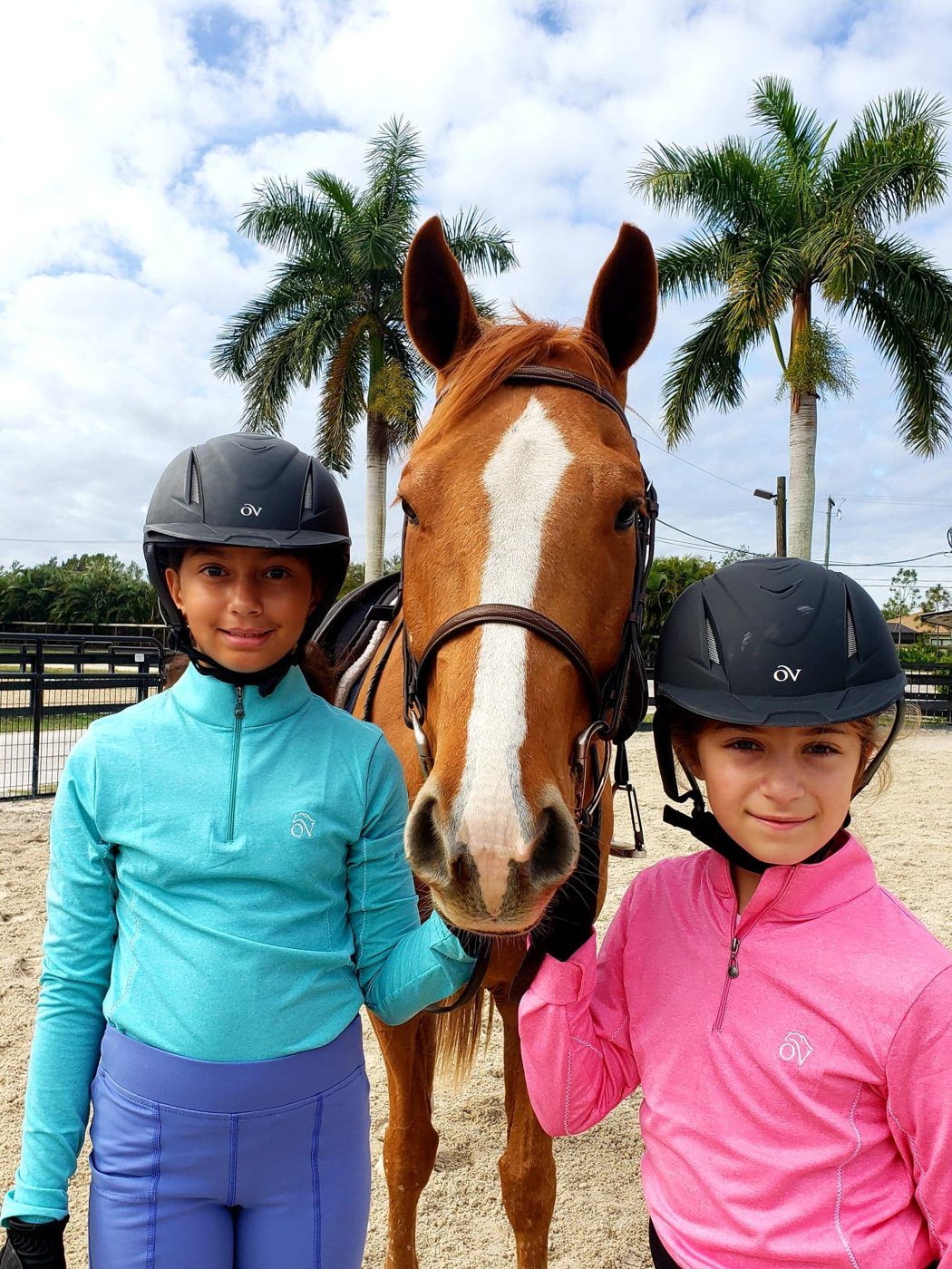 Two young campers in helmets with a chestnut horse