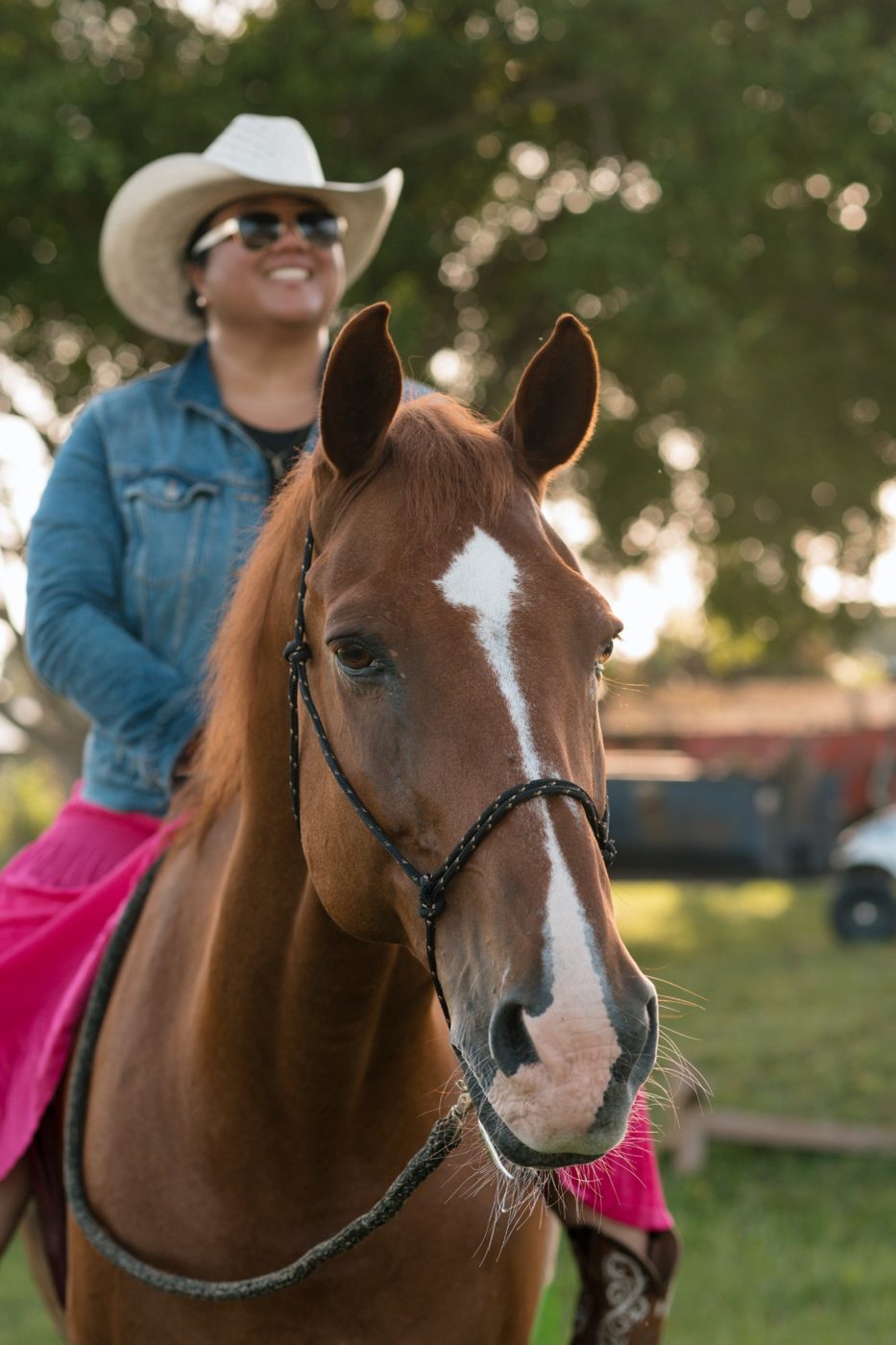 A smiling rider in a cowboy hat on a chestnut horse
