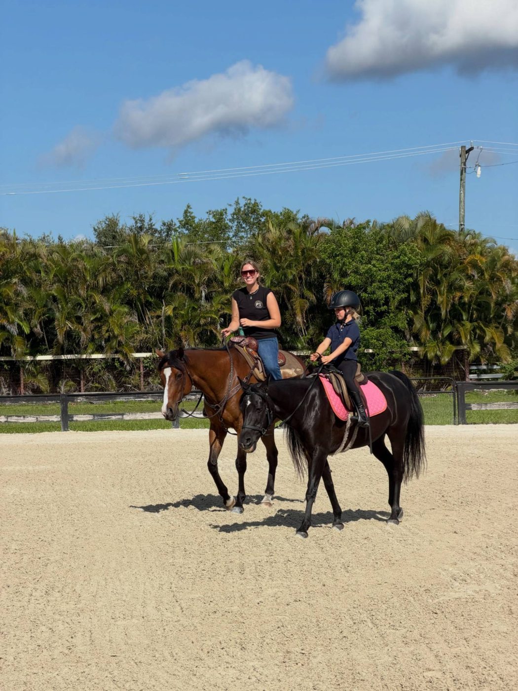 Stella riding Western beside a young rider on a black horse