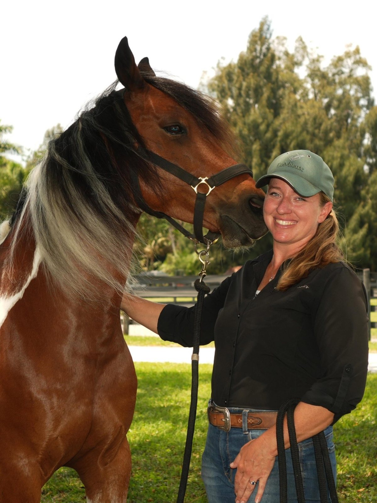 Erin Case smiling beside a bay paint horse