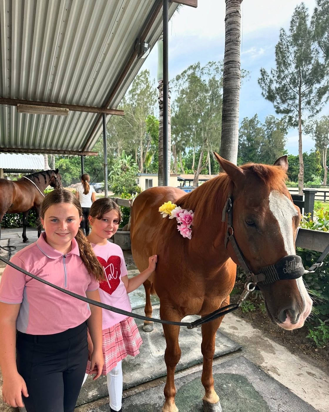 Two campers with a chestnut wearing flowers in its mane