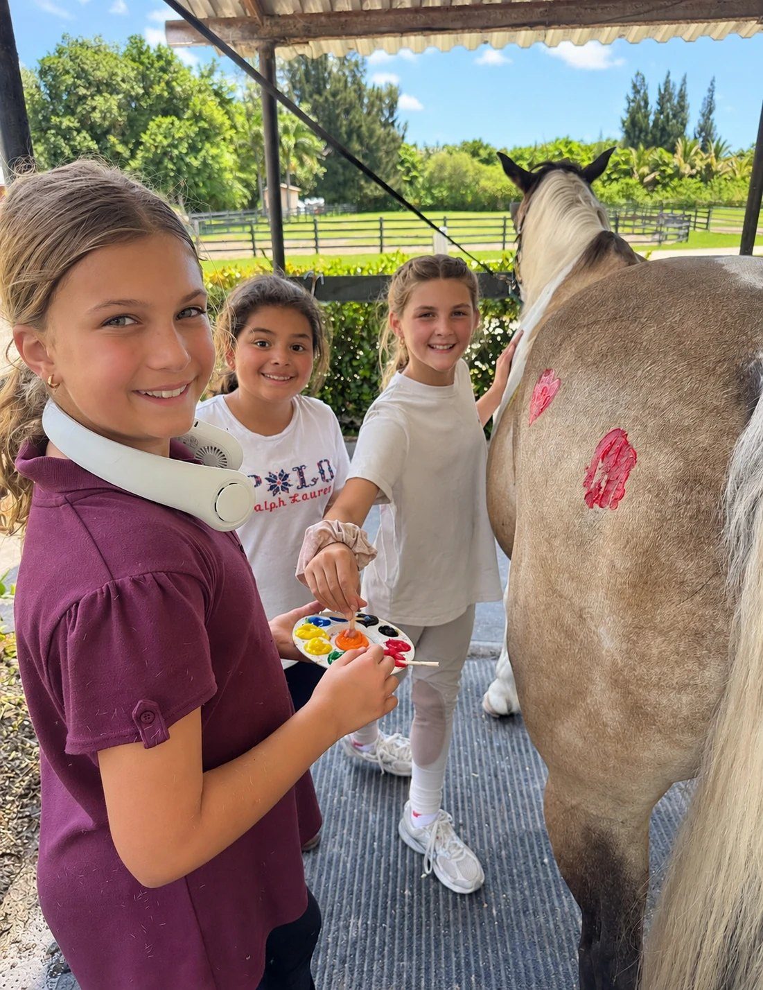 Campers painting colorful designs on a horse during barn fun