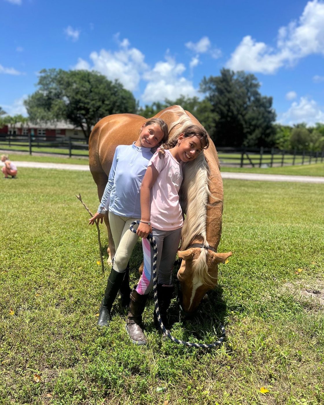 Two campers leaning on a grazing palomino